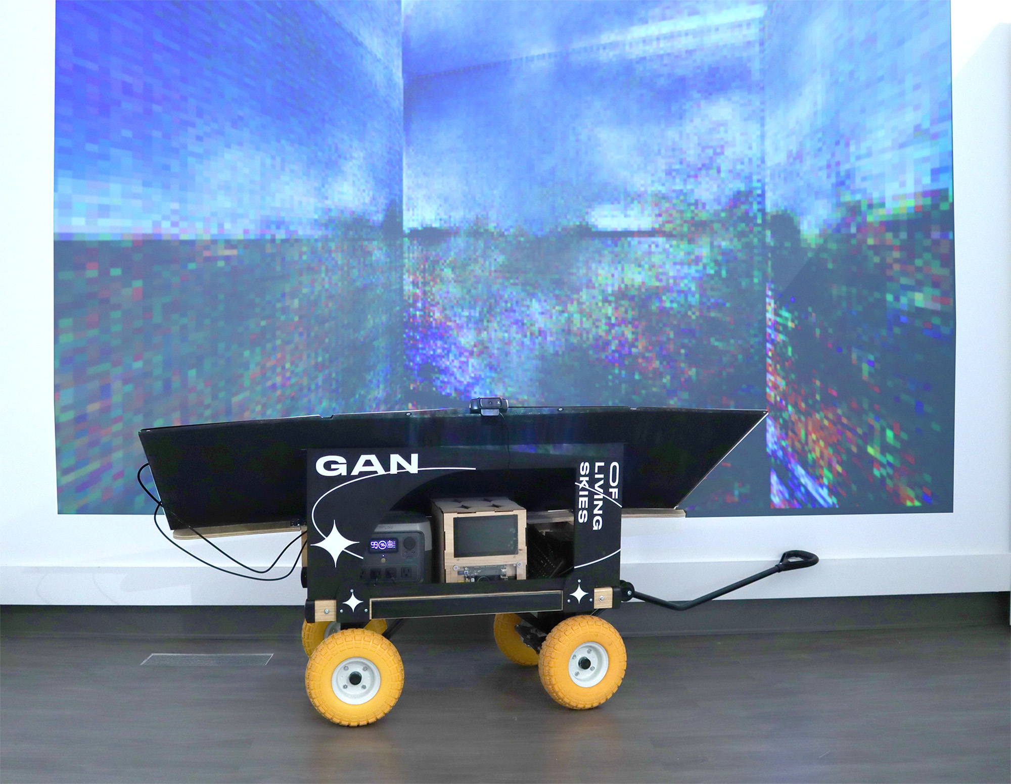 The WaGAN inside the gallery with its generative results projected on the wall behind it.